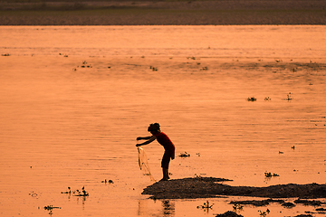 Image showing Asian Woman fishing in the river, silhouette at sunset