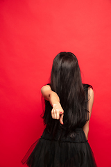 Image showing Young woman in hat and dress as a witch on red background