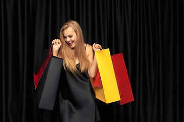 Image showing Young woman in dress shopping on black background