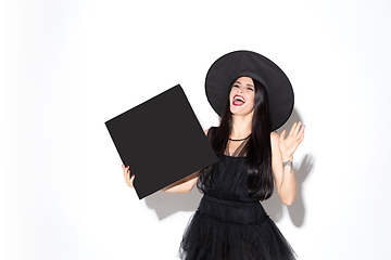 Image showing Young woman in hat and dress as a witch on white background