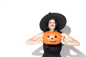 Image showing Young woman in hat and dress as a witch on white background