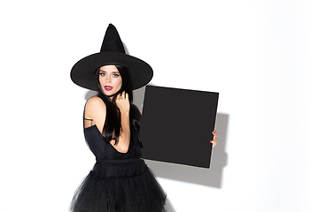 Image showing Young woman in hat and dress as a witch on white background