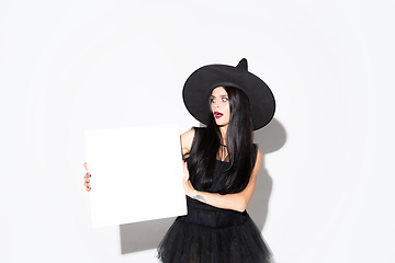 Image showing Young woman in hat and dress as a witch on white background