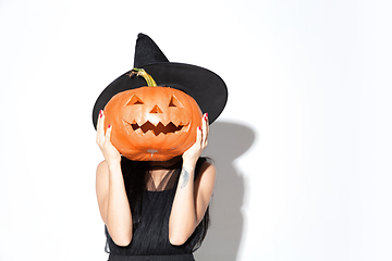 Image showing Young woman in hat and dress as a witch on white background