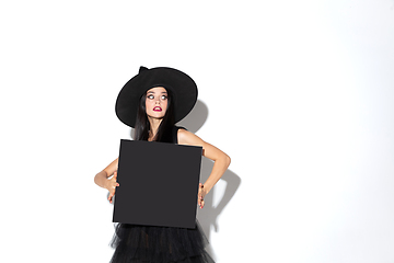 Image showing Young woman in hat and dress as a witch on white background