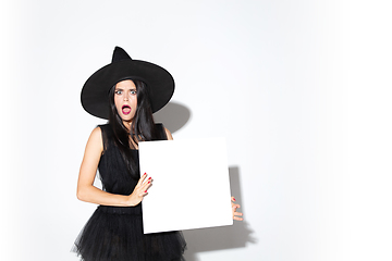 Image showing Young woman in hat and dress as a witch on white background