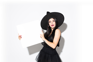 Image showing Young woman in hat and dress as a witch on white background