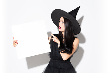 Image showing Young woman in hat and dress as a witch on white background