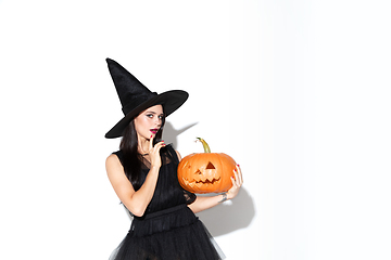 Image showing Young woman in hat and dress as a witch on white background