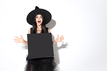 Image showing Young woman in hat and dress as a witch on white background