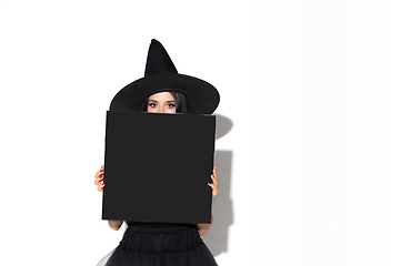 Image showing Young woman in hat and dress as a witch on white background