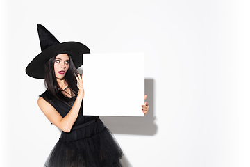 Image showing Young woman in hat and dress as a witch on white background