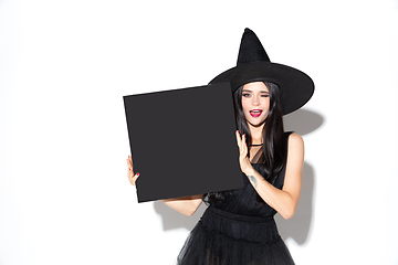 Image showing Young woman in hat and dress as a witch on white background