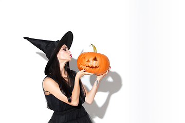 Image showing Young woman in hat and dress as a witch on white background