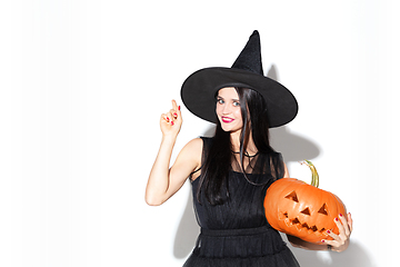 Image showing Young woman in hat and dress as a witch on white background