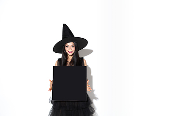 Image showing Young woman in hat and dress as a witch on white background