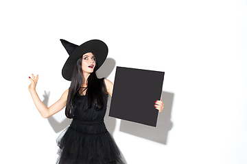 Image showing Young woman in hat and dress as a witch on white background