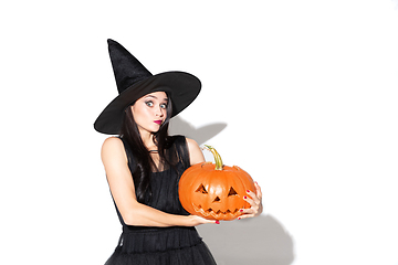 Image showing Young woman in hat and dress as a witch on white background