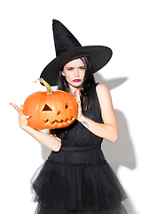 Image showing Young woman in hat and dress as a witch on white background