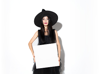 Image showing Young woman in hat and dress as a witch on white background