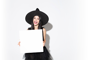 Image showing Young woman in hat and dress as a witch on white background