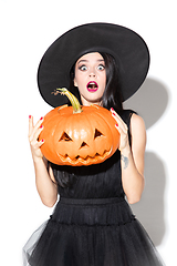 Image showing Young woman in hat and dress as a witch on white background