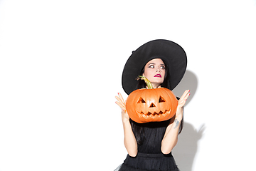 Image showing Young woman in hat and dress as a witch on white background