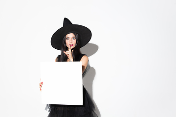 Image showing Young woman in hat and dress as a witch on white background