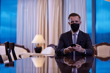 Image showing business man using smart phone at luxury office wearing face mask