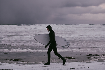 Image showing Arctic surfer going by beach after surfing