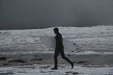 Image showing Arctic surfer going by beach after surfing