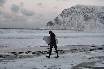 Image showing Arctic surfer going by beach after surfing