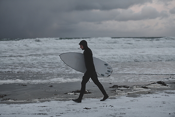 Image showing Arctic surfer going by beach after surfing