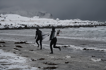 Image showing Arctic surfers running on beach after surfing