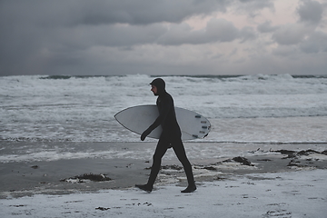 Image showing Arctic surfer going by beach after surfing