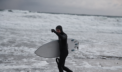 Image showing Arctic surfer going by beach after surfing