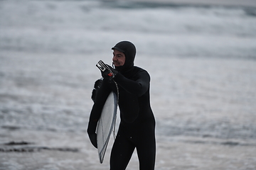 Image showing Arctic surfer going by beach after surfing