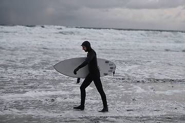 Image showing Arctic surfer going by beach after surfing