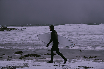 Image showing Arctic surfer going by beach after surfing