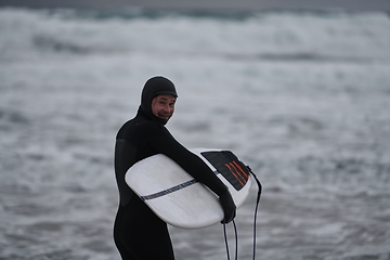 Image showing Arctic surfer going by beach after surfing