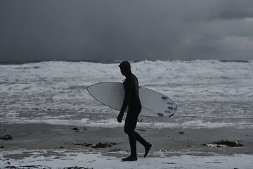 Image showing Arctic surfer going by beach after surfing