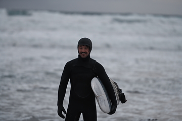 Image showing Arctic surfer going by beach after surfing