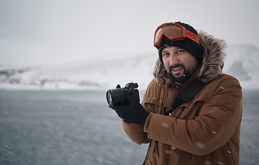 Image showing photographer at winter in stormy weather wearing warm fur jacket