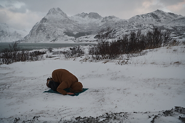 Image showing Muslim traveler praying in cold snowy winter day