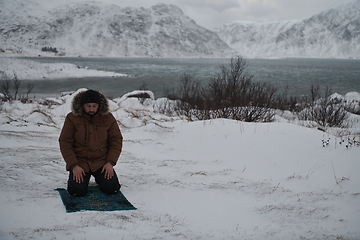 Image showing Muslim traveler praying in cold snowy winter day