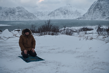 Image showing Muslim traveler praying in cold snowy winter day