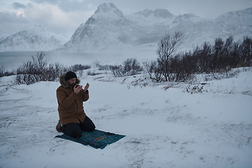 Image showing Muslim traveler praying in cold snowy winter day