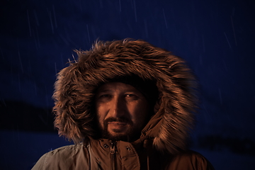 Image showing man at winter in stormy weather night wearing warm fur jacket