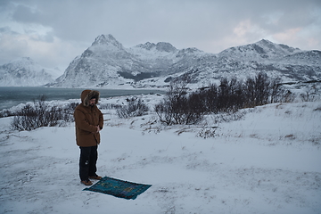 Image showing Muslim traveler praying in cold snowy winter day