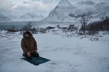 Image showing Muslim traveler praying in cold snowy winter day